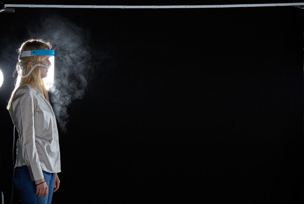 Mischa Nawrata, Fotograf, Aerosolausstoßtest, Chorverband Österreich, Aerosolausstoßtestung, Prof. Dr. Fritz Sterz, Ao.Univ.-Prof. Dr.med.univ. Fritz Sterz, fritz.sterz@meduniwien.ac.at , MedUni Wien, Universitätskliniken der MedUni Wien / AKH Wien, ao.Univ.Prof. Dr. Harald Herkner, MSc, Dr. Heinz Bixa, DDr. Karl-Gerhard Straßl MAS, Präsident, Chorverband Österreich, Mit 4-8 Liter Sauerstoff pro Minute wurde mit einer Düse in einem kleinen Behältnis mit 0,9% Kochsalz Nebel (= Aerosol) erzeugt. Mit kleinen Sonden in den Nasenöffnungen wurde den Sängern dieser Nebel kontinuierlich zusätzlich zum Atmen verabreicht. Die Verstreuung des Aerosols in den oberen Atemwegen war damit gewährleistet. In einem schwarz ausgekleideten Raum befanden sich hinter dem jeweiligen Musiker links und rechts besonders starke Scheinwerfer, um das Ausströmen der Aerosole sichtbar zu machen. Dadurch war es möglich, die Verteilung der Ausatmungsluft im Gegenlicht zu visualisieren und fotographisch zu dokumentieren, ChVOe=Chorverband Österreich, Alt, Tenor, Bass, oM=ohne Maske, mM=mit Maske, mG=mit Gesichtsschutz, mMprivat=private Schutzmaske aus Stoff genäht, FFP2 Schutzmaske, es wurden Vokale und Konsonanten gesungen,