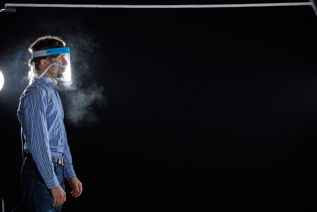 Mischa Nawrata, Fotograf, Aerosolausstoßtest, Chorverband Österreich, Aerosolausstoßtestung, Prof. Dr. Fritz Sterz, Ao.Univ.-Prof. Dr.med.univ. Fritz Sterz, fritz.sterz@meduniwien.ac.at , MedUni Wien, Universitätskliniken der MedUni Wien / AKH Wien, ao.Univ.Prof. Dr. Harald Herkner, MSc, Dr. Heinz Bixa, DDr. Karl-Gerhard Straßl MAS, Präsident, Chorverband Österreich, Mit 4-8 Liter Sauerstoff pro Minute wurde mit einer Düse in einem kleinen Behältnis mit 0,9% Kochsalz Nebel (= Aerosol) erzeugt. Mit kleinen Sonden in den Nasenöffnungen wurde den Sängern dieser Nebel kontinuierlich zusätzlich zum Atmen verabreicht. Die Verstreuung des Aerosols in den oberen Atemwegen war damit gewährleistet. In einem schwarz ausgekleideten Raum befanden sich hinter dem jeweiligen Musiker links und rechts besonders starke Scheinwerfer, um das Ausströmen der Aerosole sichtbar zu machen. Dadurch war es möglich, die Verteilung der Ausatmungsluft im Gegenlicht zu visualisieren und fotographisch zu dokumentieren, ChVOe=Chorverband Österreich, Alt, Tenor, Bass, oM=ohne Maske, mM=mit Maske, mG=mit Gesichtsschutz, mMprivat=private Schutzmaske aus Stoff genäht, FFP2 Schutzmaske, es wurden Vokale und Konsonanten gesungen,